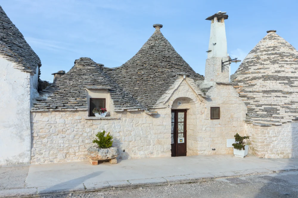 Ruelle calme et résidentielle du Rione Aia Piccola, trulli aux façades blanches avec pots de géraniums, idéal pour Visiter Alberobello, Pouilles