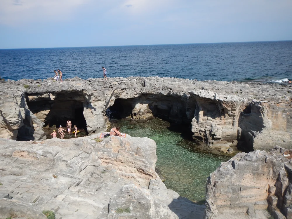 Piscine naturelle de Marina Serra avec eau turquoise et arche de calcaire naturelle, côte rocheuse du Salento, extrême sud des Pouilles, Italie
