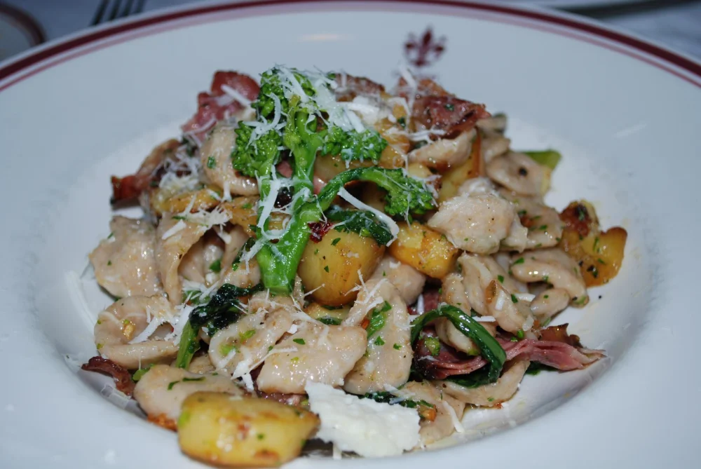Orecchiette alle cime di rapa servies dans une assiette blanche, spécialité emblématique des Pouilles à base de pâtes fraîches et pousses de navet