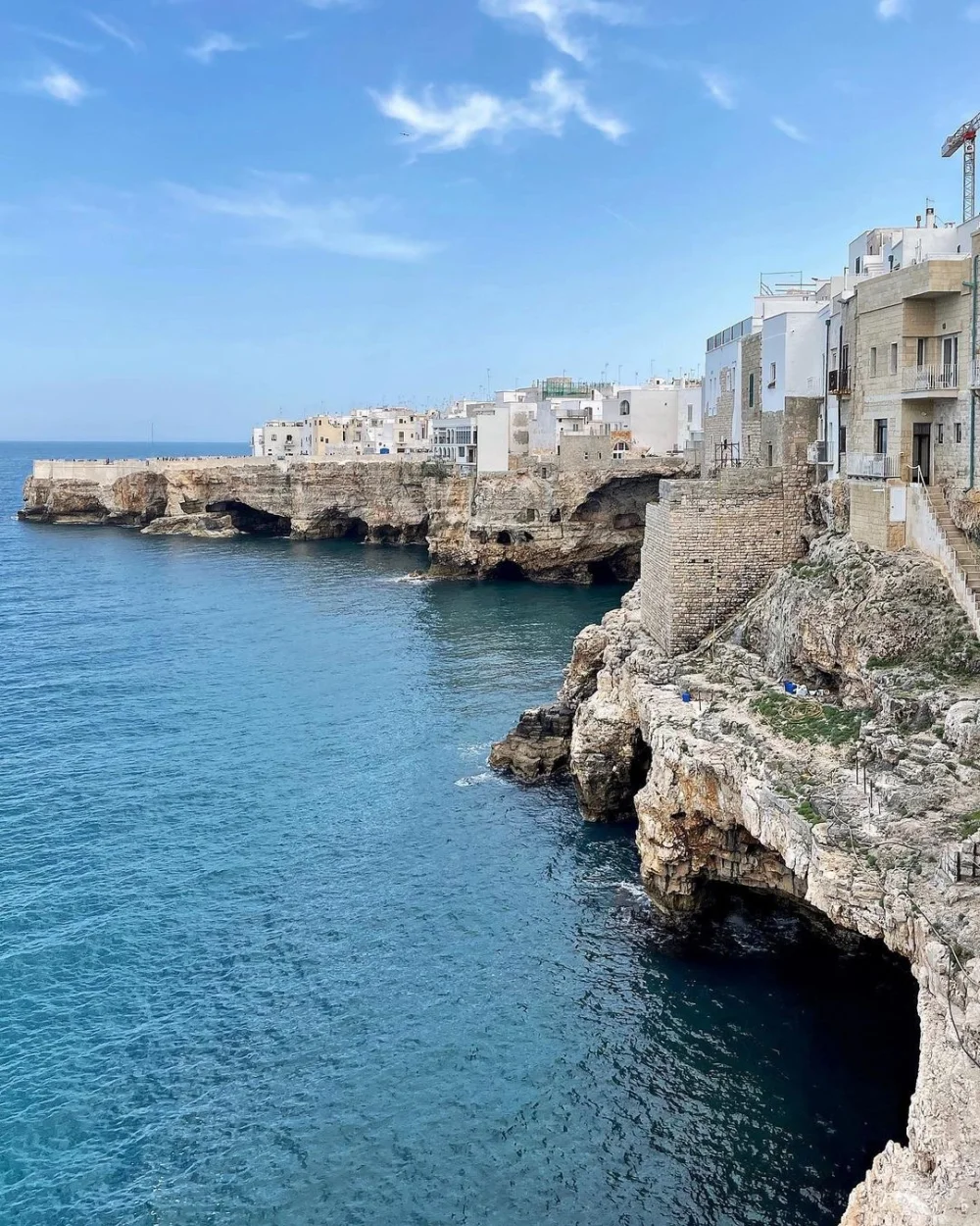 Vue panoramique sur les falaises de Polignano a Mare depuis la mer, vieille ville accrochée sur la roche calcaire, Pouilles