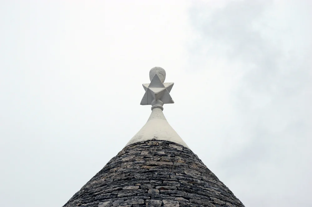 Sommet d'un trullo d'Alberobello avec ses symboles mystérieux peints à la chaux sur le cône de pierre calcaire, Pouilles, Italie