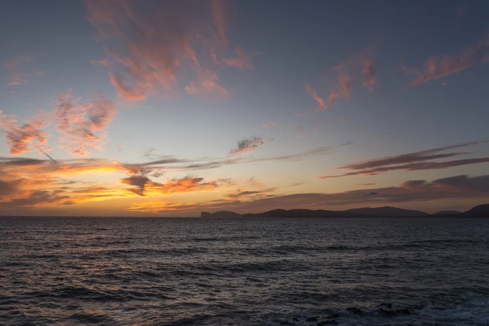 Les remparts d'Alghero au coucher du soleil avec des passants et la mer, Sardaigne