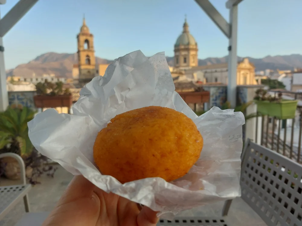 Arancina alla Norma, street food sicilienne traditionnelle,Palerme, Sicile, illustrant la différence de budget pour chosiir entre Sicile ou Sardaigne