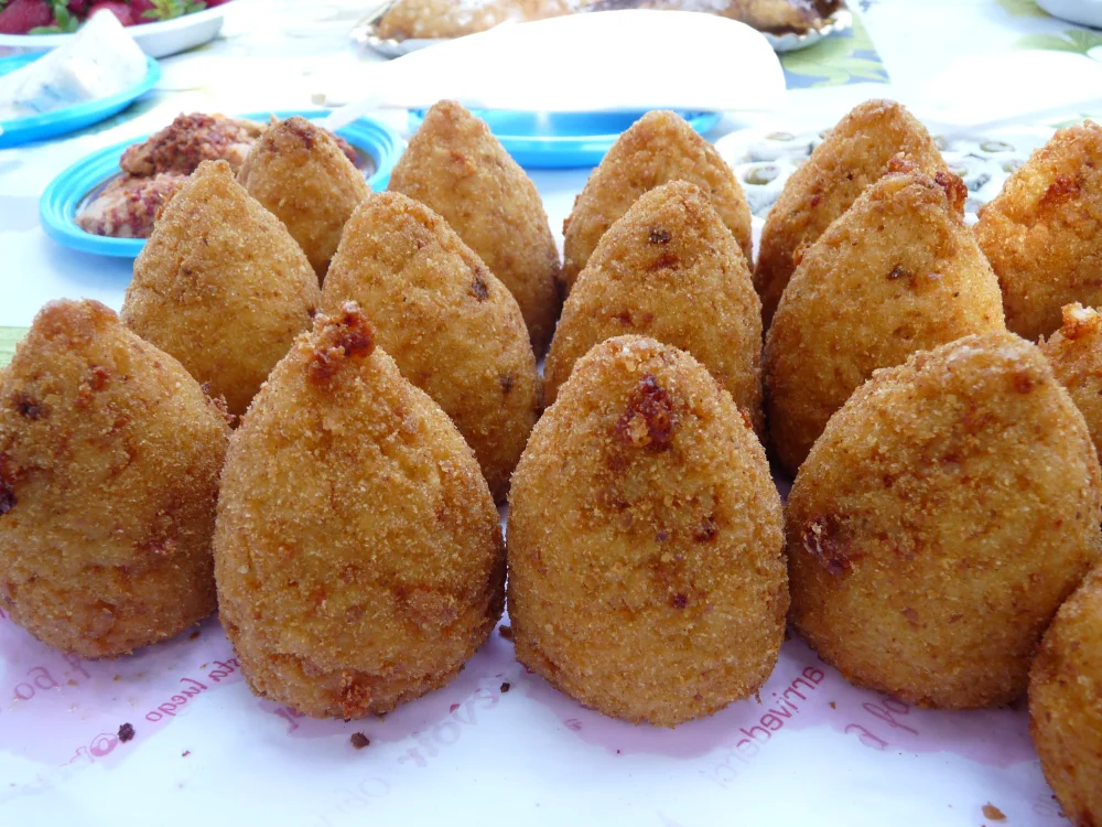 Arancini frits en forme de cône sur un marché sicilien, spécialité de street food de Sicile orientale