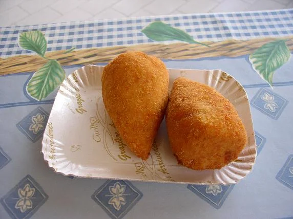Arancini frits au ragù sur un étal du marché d'Ortygie, street food incontournable de la Sicile, Syracuse