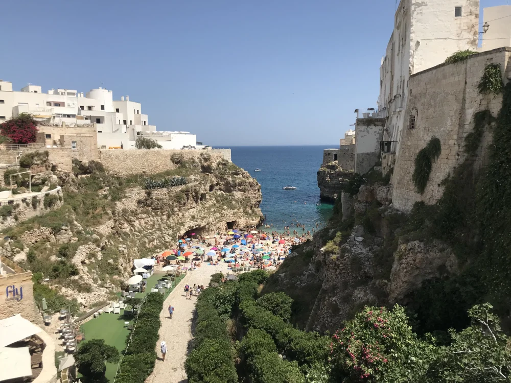 Plage de Lama Monachile à Polignano a Mare en pleine saison estivale, crique encaissée entre les falaises calcaires, Pouilles