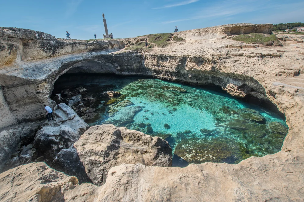Vue plongeante sur le gouffre naturel de la Grotta della Poesia et ses eaux cristallines, site archéologique de Roca Vecchia, Pouilles