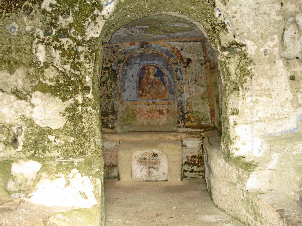 Intérieur sombre et mystérieux d'une église rupestre à Matera, fresques byzantines à moitié effacées sur la roche brute, Basilicate