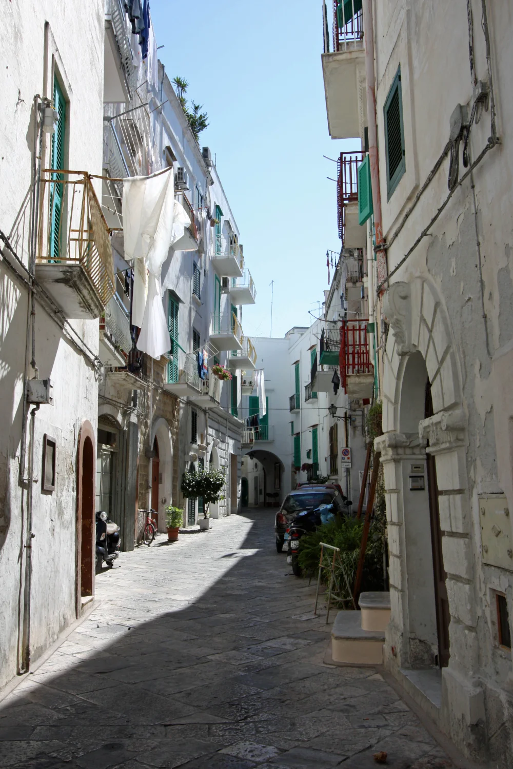 Ruelle pavée du centre historique de Monopoli, maisons blanches et linge aux fenêtres, Puglia