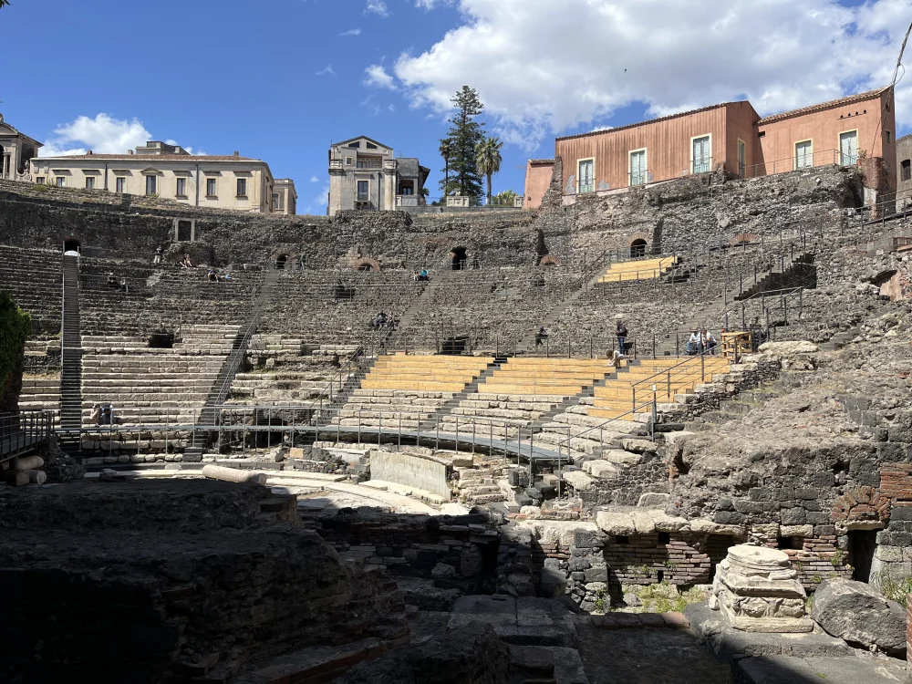 Gradins du théâtre gréco-romain de Catane en pierre de lave noire, encaissés entre des immeubles résidentiels, Sicile