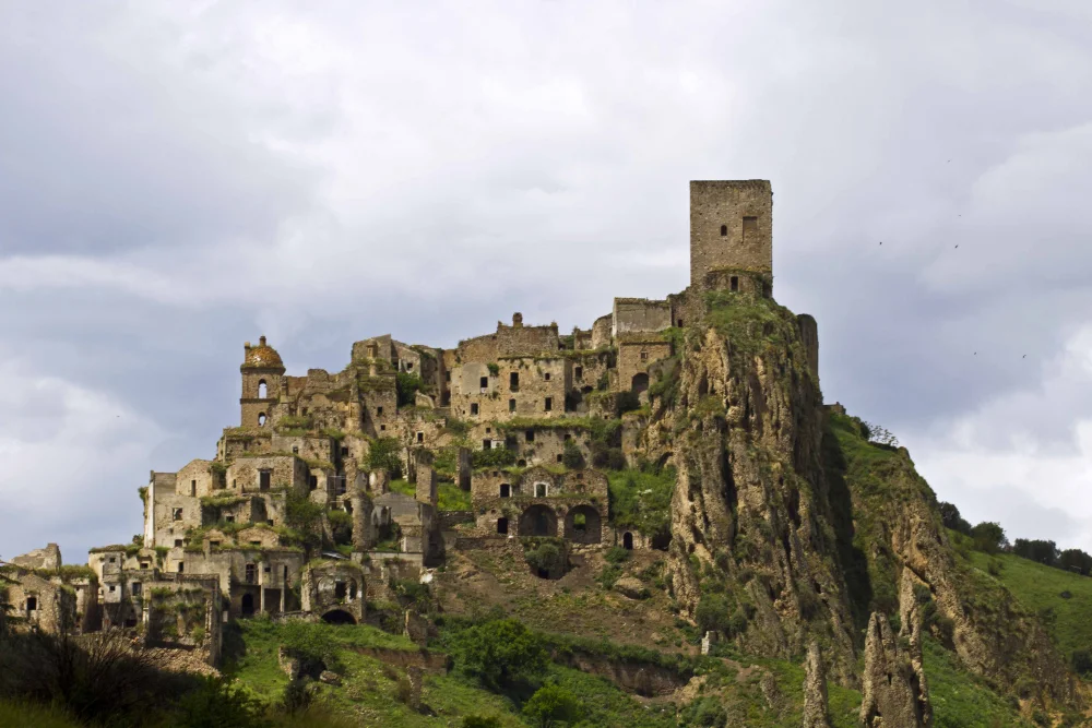 Ruines de l'église et du donjon de Craco dominant le paysage lunaire et asséché des calanchi d'argile, Basilicate