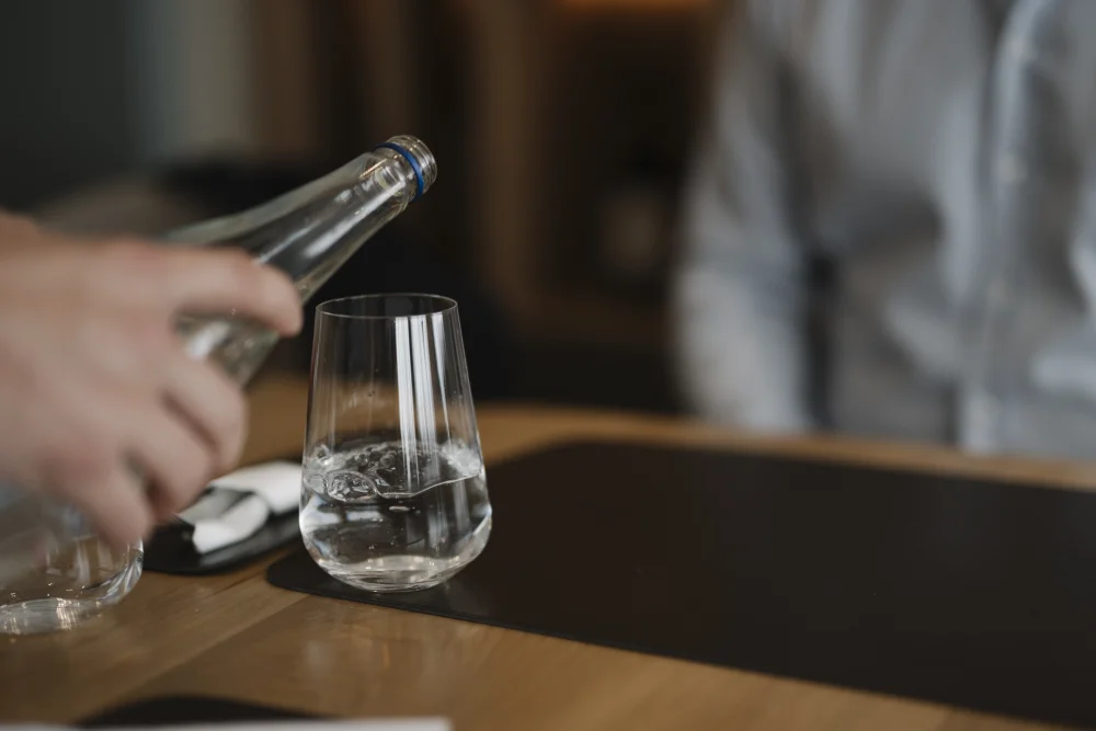 Serveur versant de l'eau minérale dans un verre sur une table de restaurant en Sardaigne, Italie
