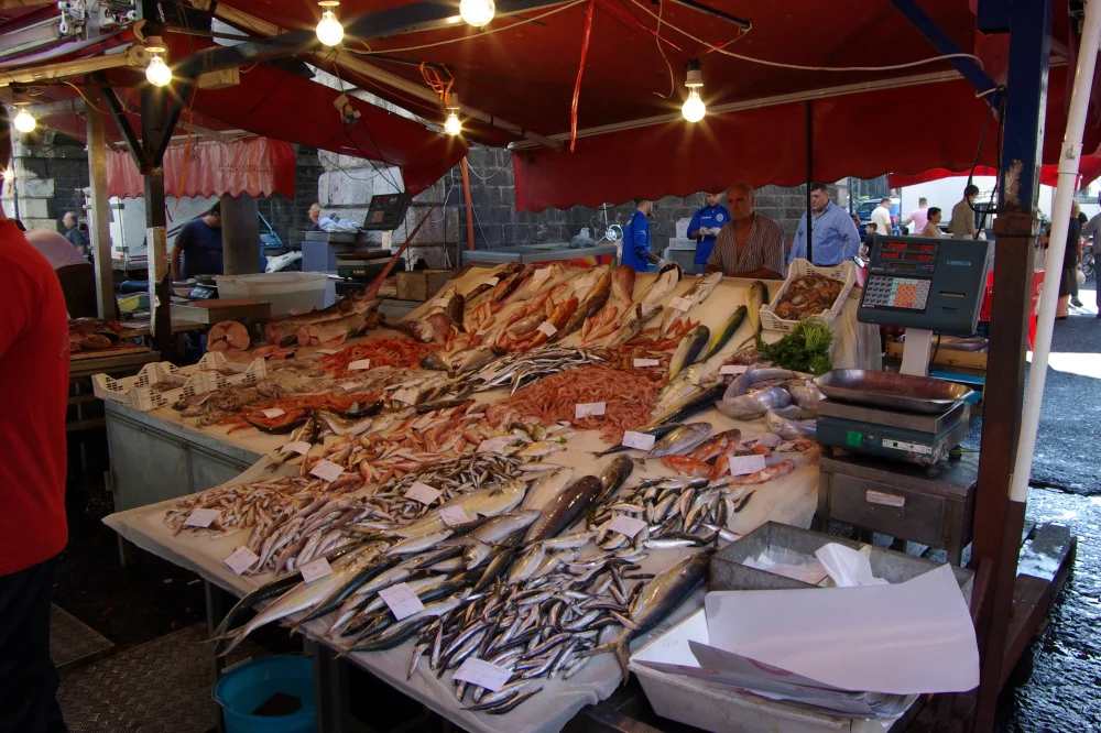 Marché aux poissons de Catane (La Pescheria), étals sous bâches rouges et architecture en basalte noir, Sicile, première étape de l'itinéraire sur 5 jours en Sicile sans voiture au départ de Catane