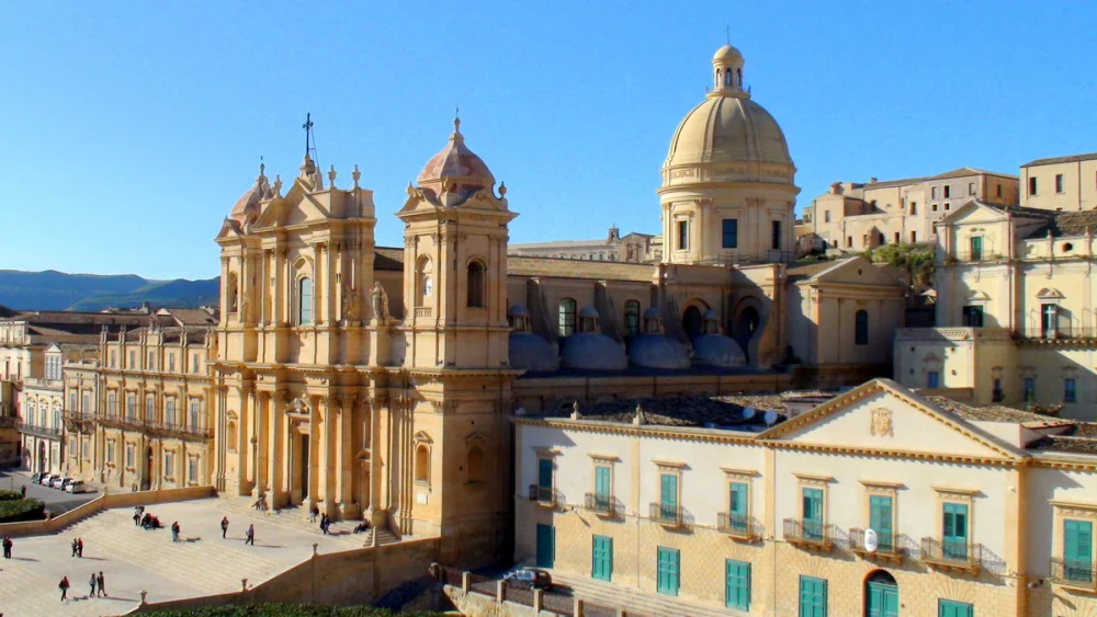 Façade baroque en tuf calcaire doré de Noto et ses balcons ornementés sous la lumière de fin de journée, Sicile