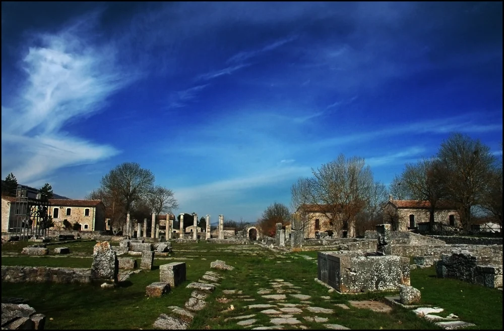 Colonnes romaines d'Altilia Sepino au milieu de l'herbe, bergeries en pierre en arrière-plan