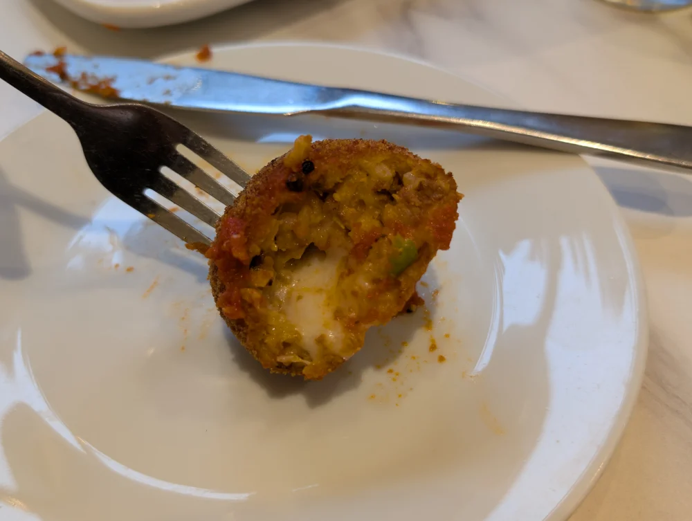 Arancina sicilienne entamée, coque frite dorée et garniture au ragoût, Palerme