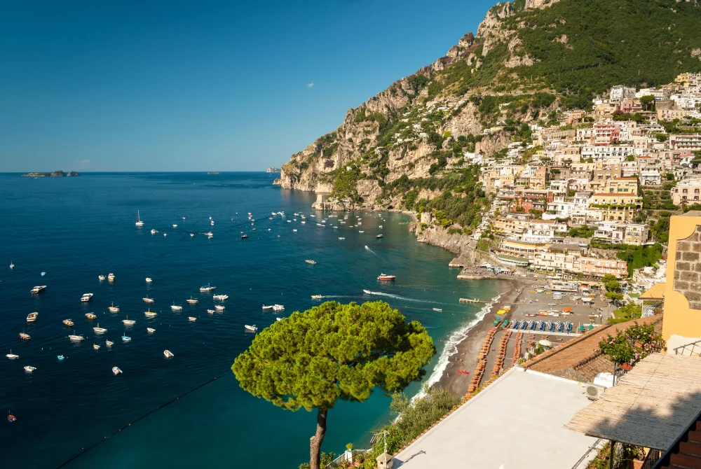Parasols orange et bleus alignés sur la Spiaggia Grande de Positano face aux maisons colorées, Côte Amalfitaine