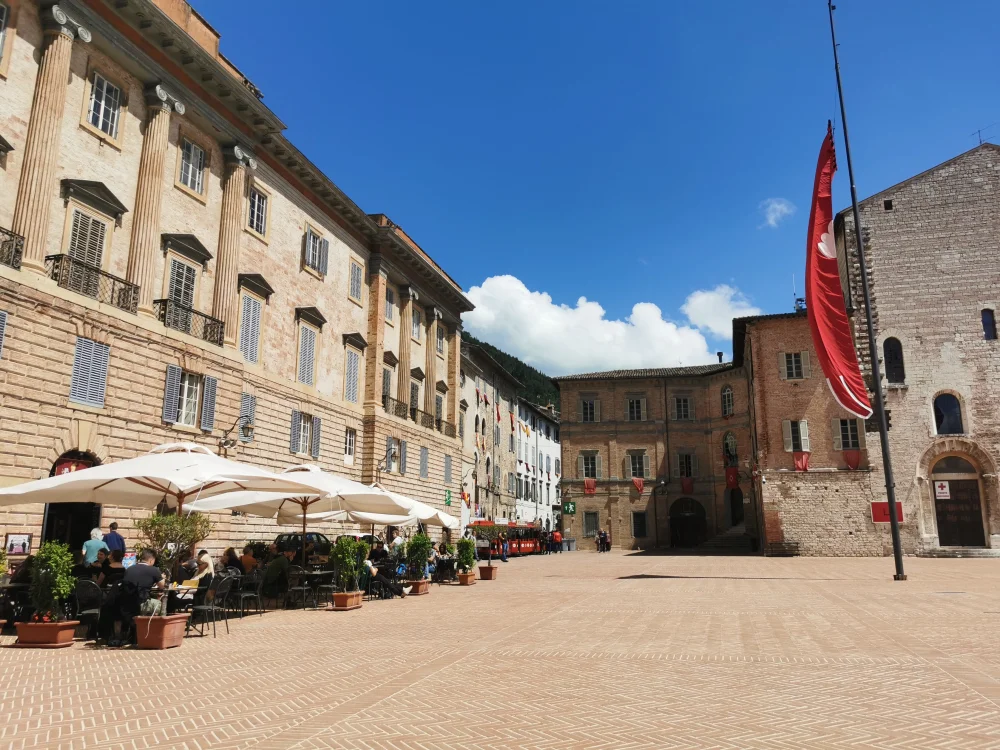 Piazza Grande de Gubbio bordée de façades médiévales, quartier des hébergements du centre historique