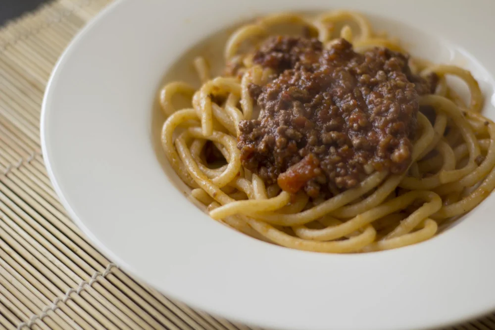 Pici al ragù di cinghiale, spécialité de pâtes siennoises, servis dans une assiette