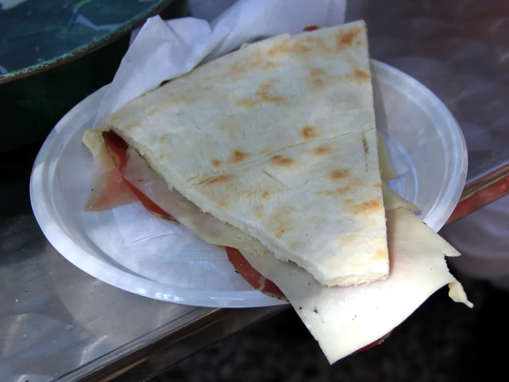Torta al testo garnie de jambon et fromage, spécialité de galette ombrienne cuite sur disque de fonte